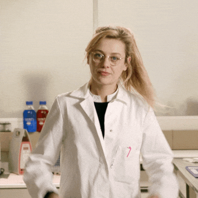Blond white woman in lab coat putting fingers to head in a ‘mind blown’ gesture