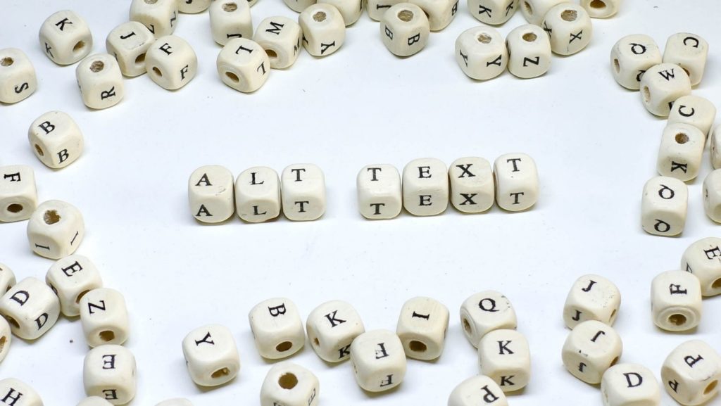 a white surface with lettered die that spells out alt text